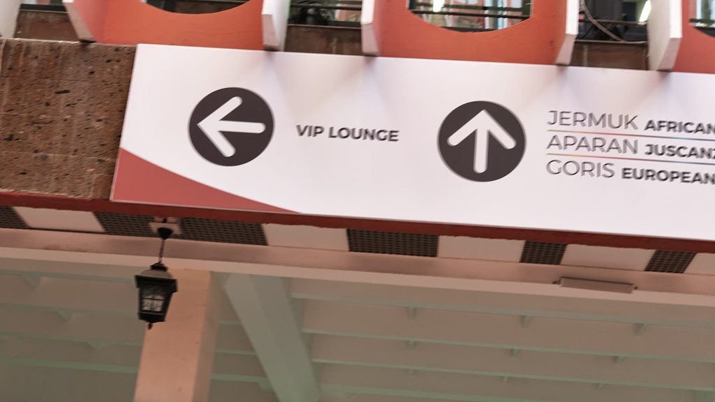 A direction board under an arcade, with an arrow to the left for the VIP lounge and an arrow straight ahead for the rooms Jermuk, Aparan and Goris.
