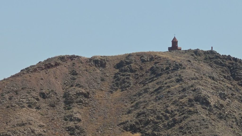 A low hill rising from the flat Ararat plain, seen from the road.