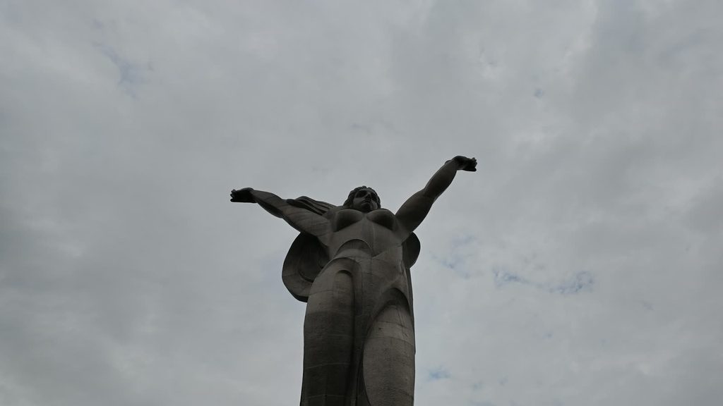 The statue with both arms thrown wide open, palms facing outward over the valley.