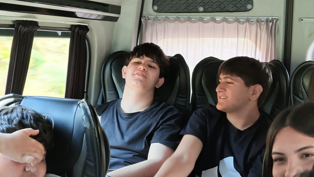 Passengers in their seats, turned towards the front of the bus, listening.