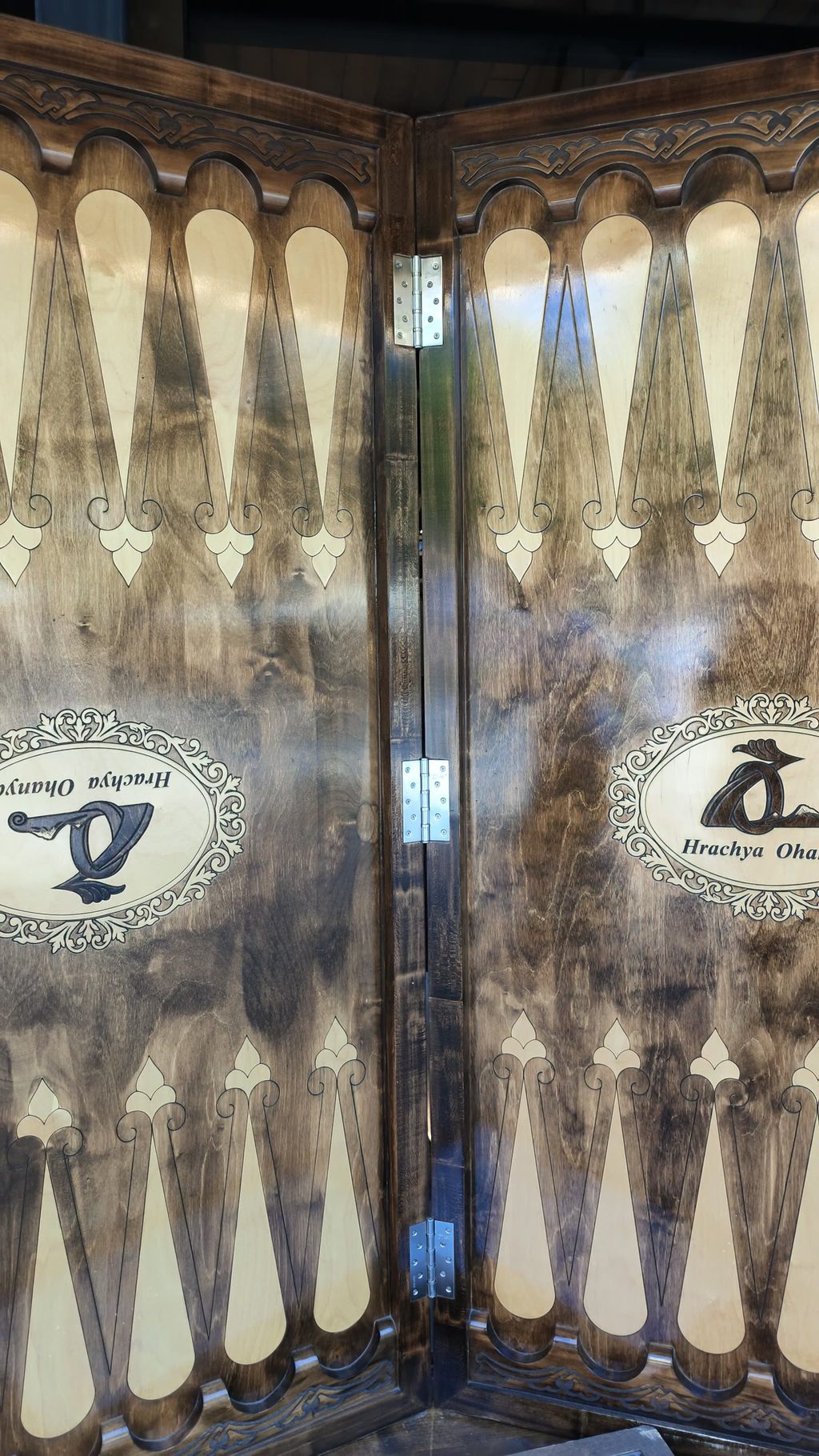 A backgammon board standing upright, taller than a person, its points inlaid.