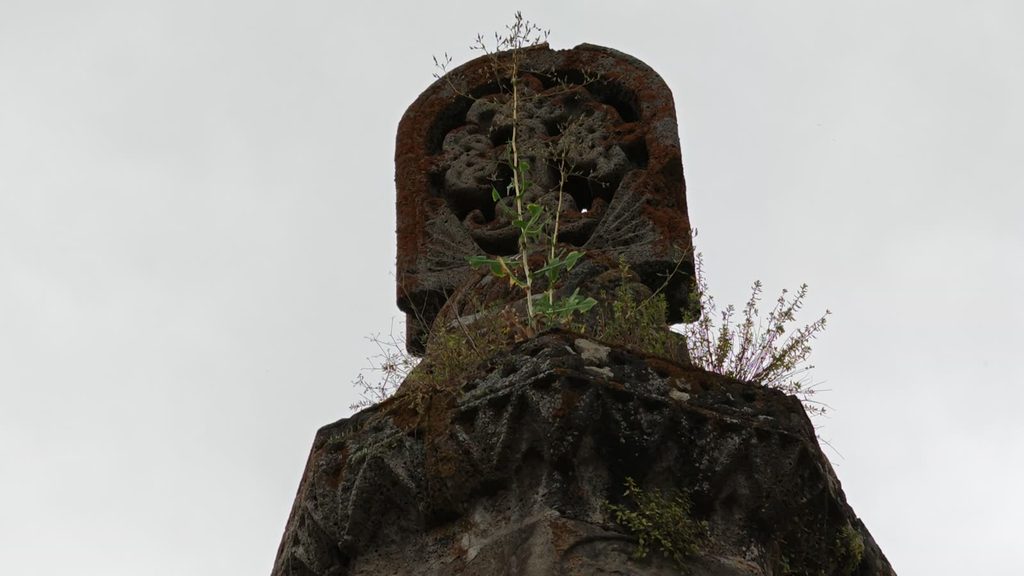 The Gavazan, a tall octagonal stone column topped with a khachkar, in the monastery courtyard.