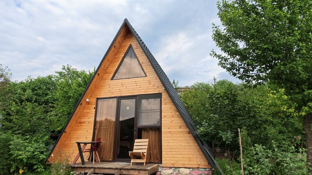 A wooden A-frame cabin against the sky, a triangular window at its apex.