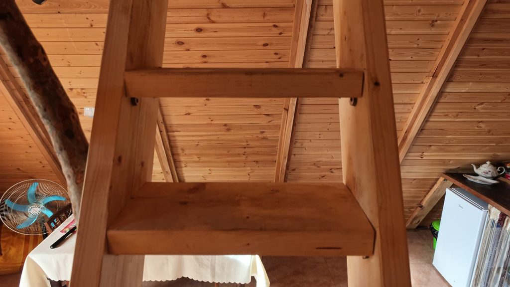 A wooden ladder leading up to the sleeping loft inside the cabin.