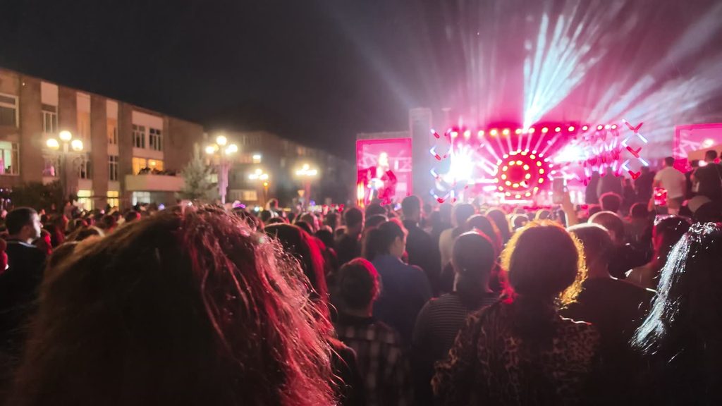 A crowd filling Memorial Park in Goris at night, the stage lit in the distance.