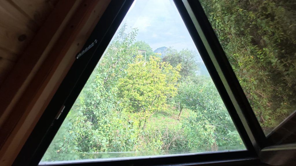 The triangular window at the apex of the cabin, framing the mountain outside.